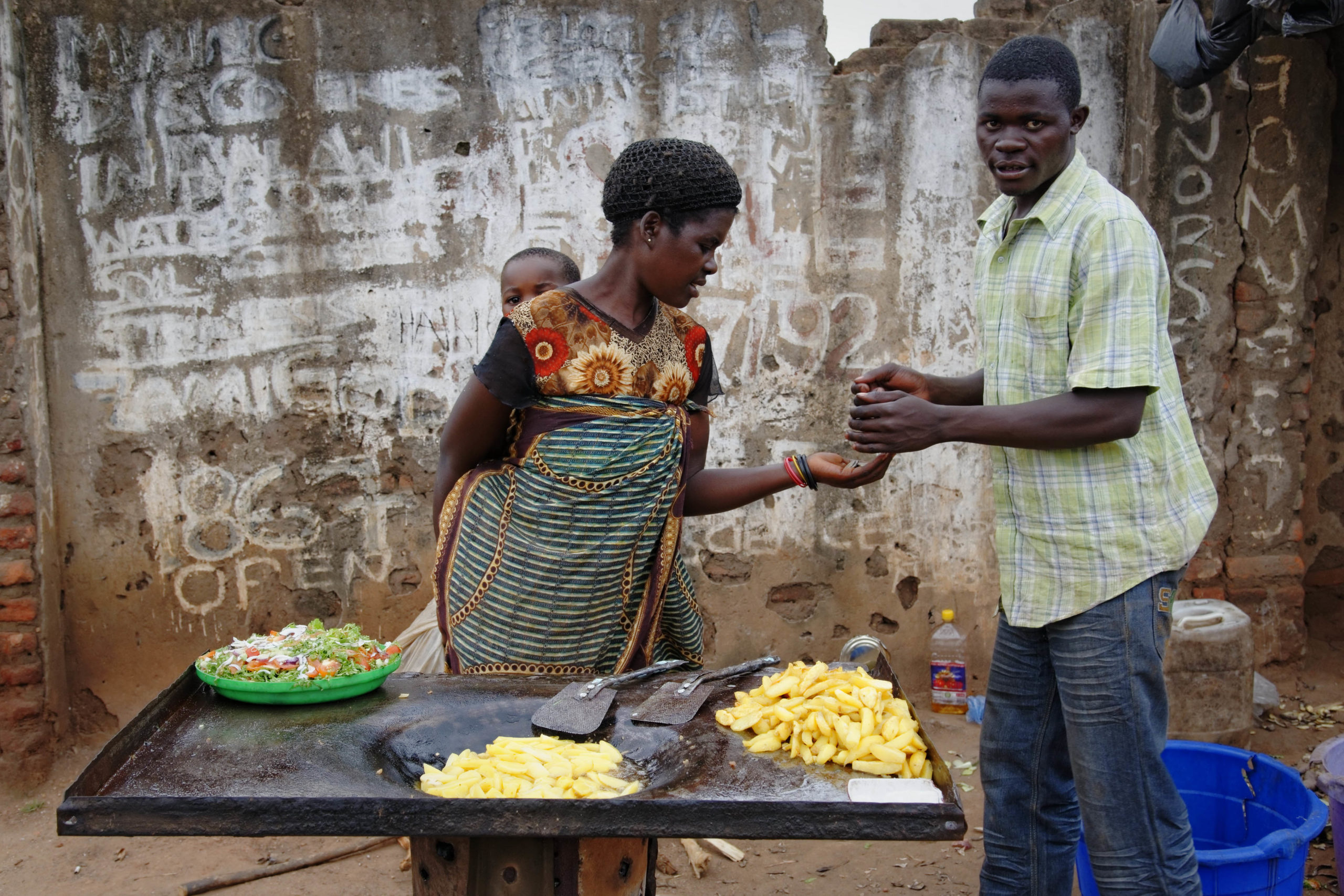 A woman carries her young son as she sells food at a market in Malawi's capital Lilongwe