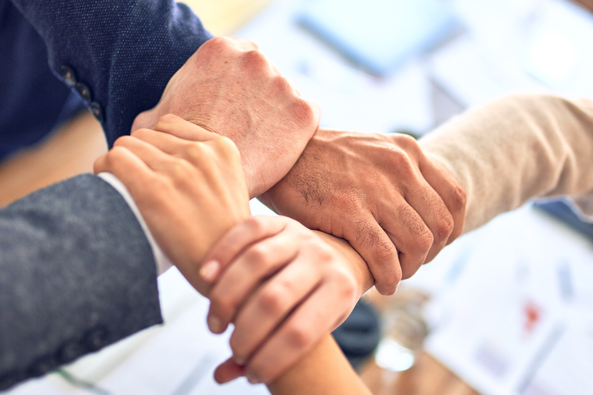 Group of business workers standing with hands together doing symbol at the office