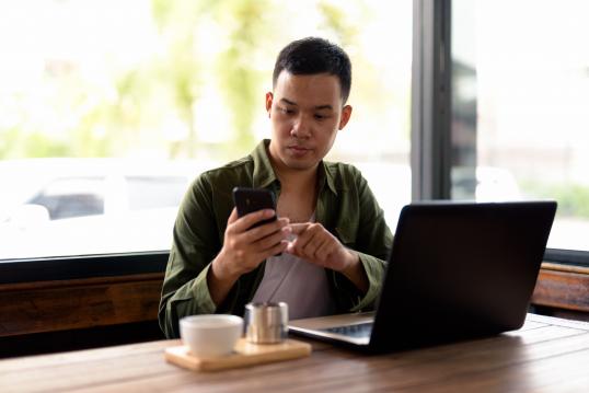 Young Asian man using mobile phone in a coffee shop