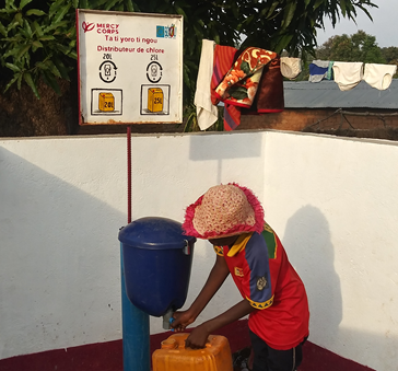 Un petit garçon utilisant le distributeur de chlore pour traiter son eau de boisson