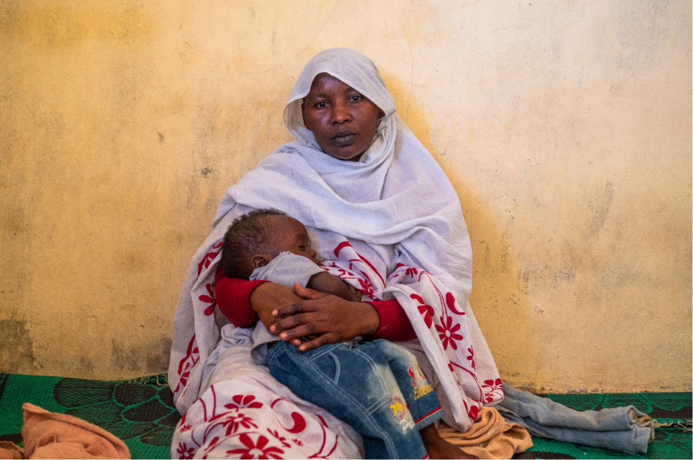 Aicha rests with her son in the nursery