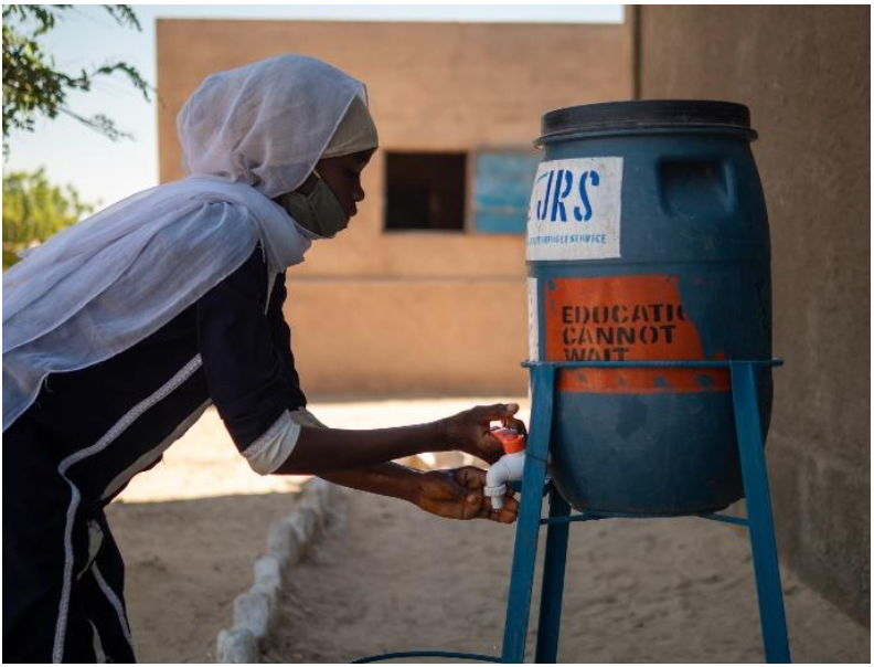 A girl washes her hands before going into class in Kounoungou refugee camp