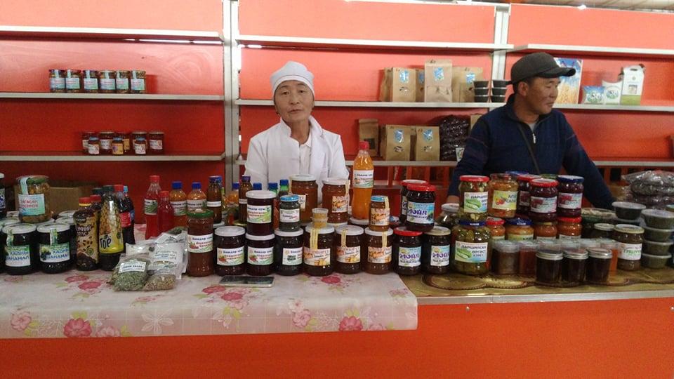 A woman and a man behind a desk selling agricultural products