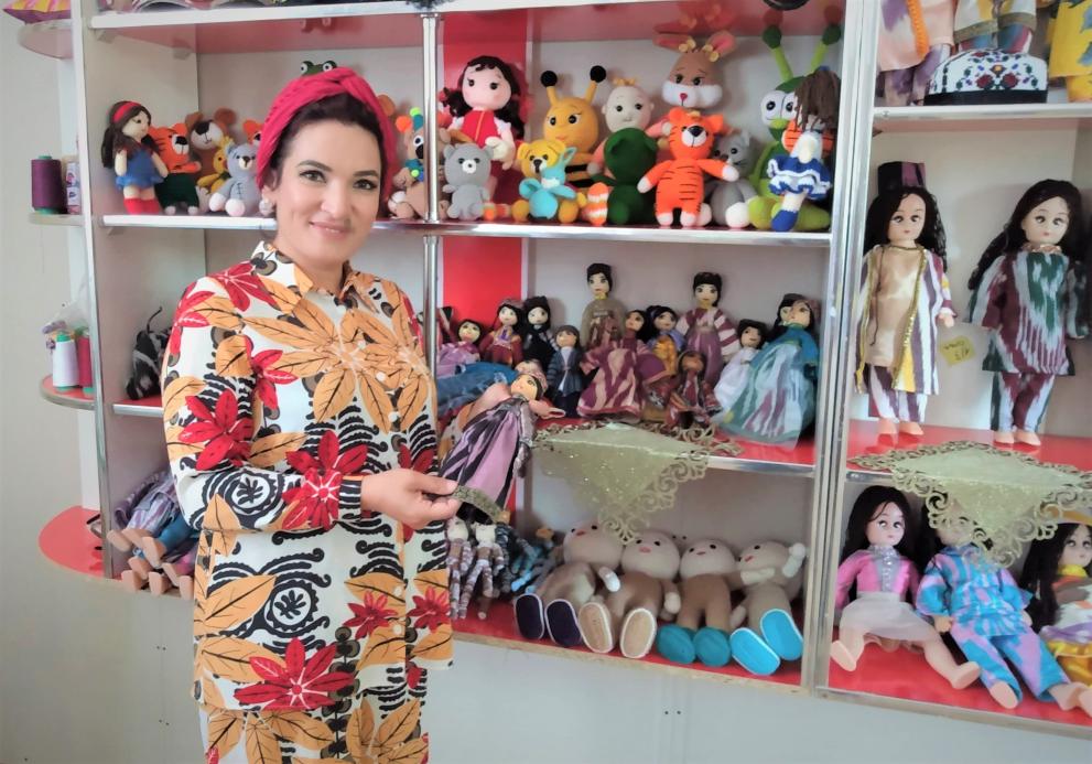 Sadokat standing in front of a shelf full of hand-made dolls