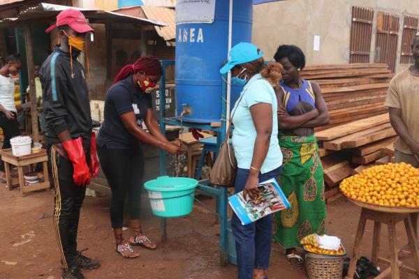 Des personnes au tour d'une station de lavage de mains au marché de Petevo à Bangui