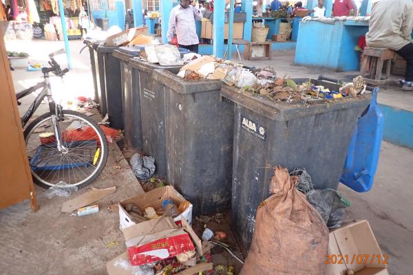 Bins full of trash at a food market in The Gambia